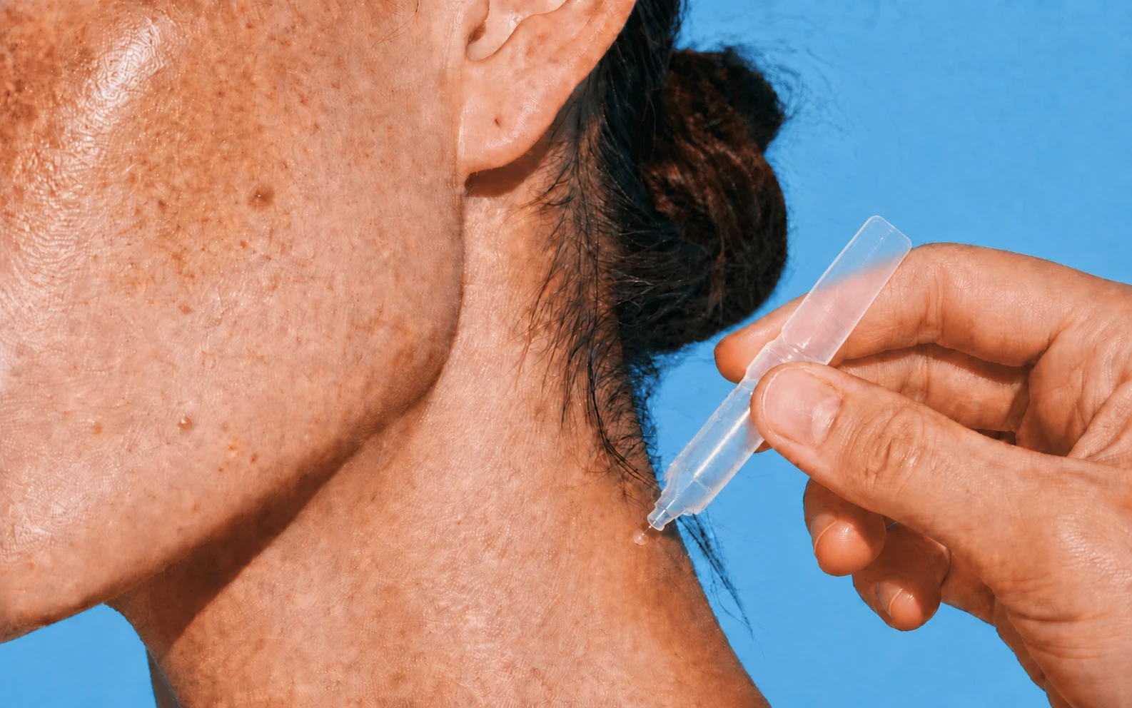 A single transparent BFS skincare ampoule dispensing one dose onto the skin